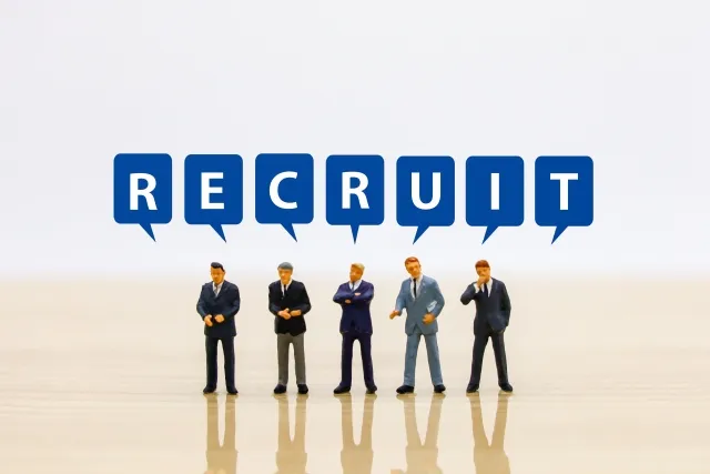 「RECRUIT」の文字の吹き出しの下に並ぶ、スーツ姿の人形